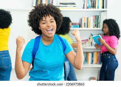 Cheering Black Female Student With Group Of African American College Students Indoors At Library