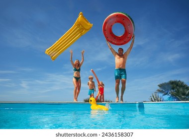 Cheering children accompanied by parents engaging in playful activities with water inflatables beside a pool - Powered by Shutterstock