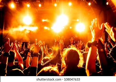 cheering crowd in front of bright yellow stage lights - Powered by Shutterstock