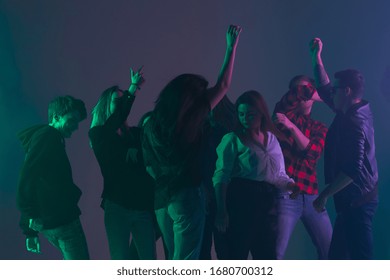 Cheering dance party, performance concept. Crowd shadow of people dancing with neon colorful lights raised hands up on dark background. Celebration, holiday, weekend, nightlife and positive vibes.