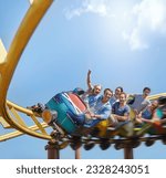 Cheering friends riding roller coaster at amusement park