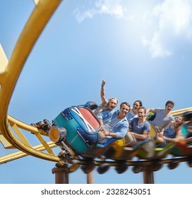 Cheering friends riding roller coaster at amusement park