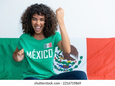 Cheering Mexican Female Soccer Fan With Flag Of Mexico Indoors At Home