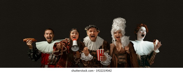 Cheering, screaming, eating. Medieval people as a royalty persons in vintage clothing on dark background. Concept of comparison of eras, modernity and renaissance, baroque style. Creative collage.