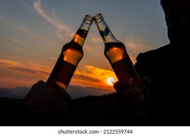 Cheering Toast Beverage Alcoholic Drink Bottles In Beautiful Evening Dark And Moody Sunset Silhouette Scene