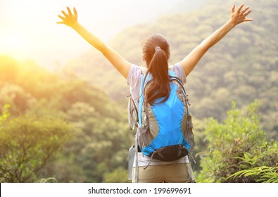 cheering woman hiker open arms at mountain peak - Shutterstock ID 199699691