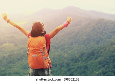 cheering woman hiker open arms at mountain peak - Shutterstock ID 398852182