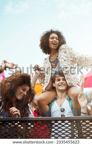 Cheering woman on man shoulders at music festival