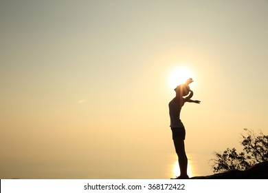 cheering woman open arms at sunset mountain peak