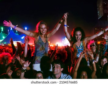 Cheering women on mens shoulders at music festival - Powered by Shutterstock