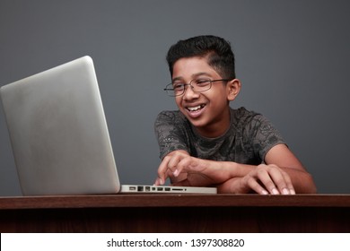Cheering young boy of Indian origin using laptop