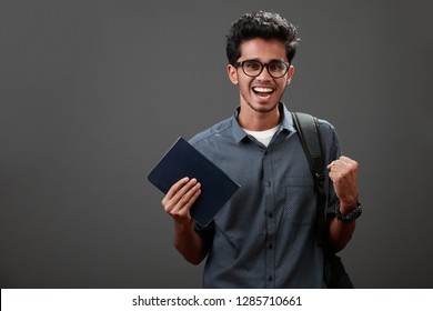 Cheering young man of Indian origin with a book in his hand