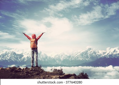 cheering young woman hiker open arms to beautiful snow mountain summits