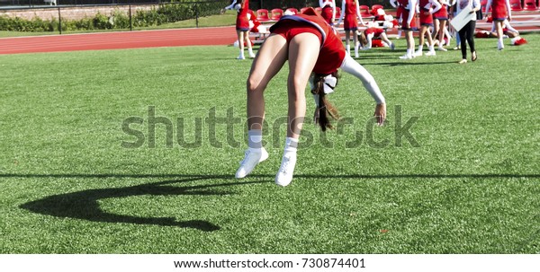 A cheerleader is\
practicing back flips while getting ready for homecoming at a local\
high school.