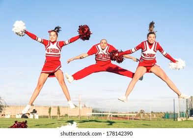 Cheerleaders Team With Male Coach Performing A Synchronized Jump