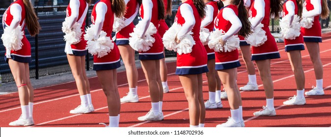 Cheerleading squad performing a routine in fron of the home fans at a high school football game.