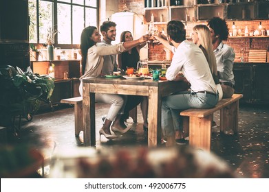 Cheers to the best friends! Group of cheerful young people cheering with champagne flutes and looking happy while while sitting at the dinning table together - Powered by Shutterstock