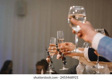 Cheers. Bride is holding glass of white wine outdoors and groom hold champagne. Wedding celebration party.  People celebrate and raise glasses for toast. Group of man and woman cheering with champagne