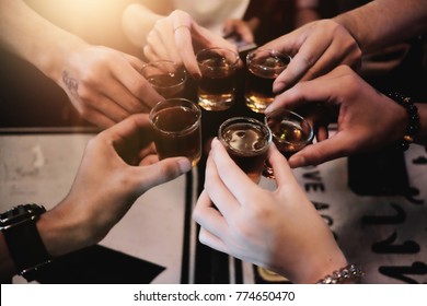 Cheers clinking of friends with bourbon whisky drink in party night after work on colorful background