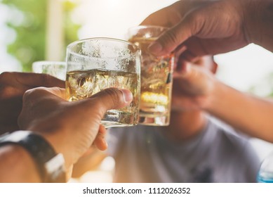Cheers clinking of friends with  whisky drink in party evening after work
