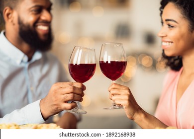 Cheers. Closeup of beautiful smiling young american couple drinking red wine, holding glasses and toasting, having romantic dinner, spending time together. Young black family celebrating