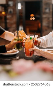 Cheers with colorful cocktails raised high, celebrating together at a vibrant gathering