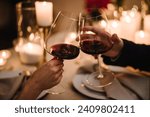 Cheers. Couple in love drinking wine. Romantic date by candlelight at night. Hands man and woman hold glasses at home. Toast. Dinner setup table for couple on Valentine