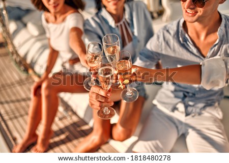 Cheers! Cropped image of group of friends relaxing on luxury yacht and drinking champagne. Having fun together while sailing in the sea. Traveling and yachting concept.