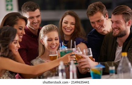 Cheers To Friday Night. Shot Of A Happy Group Of Friends Having Drinks At A Bar Together.