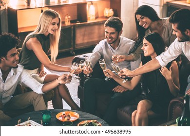 Cheers To Friends! Cheerful Young People Enjoying Food And Drinks While Spending Nice Time In Cofortable Chairs On The Kitchen Together