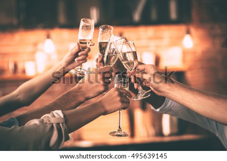 Cheers! Group of people cheering with champagne flutes with home interior in the background
