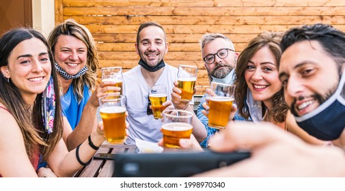 Cheers! Group Of Six Friends Makes Selfie At The Pub With Beer In Hand Smiling Happily. Return To Normal Life