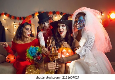 Cheers  Happy young people drinking   having fun at Halloween party  Multiracial group excited adult friends disguised in spooky outfits sitting sofa   raising flute glasses to spooky season