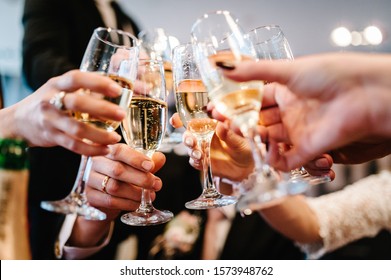 Cheers! People celebrate and raise glasses of wine for toast. Group of man and woman cheering with champagne.