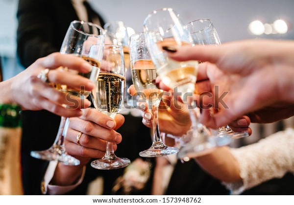 Cheers! People\
celebrate and raise glasses of wine for toast. Group of man and\
woman cheering with\
champagne.