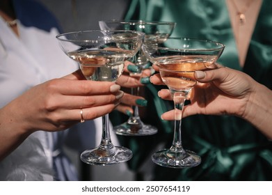 Cheers. Pretty young ladies friends wear silk robes hold glasses with champagne in hotel. Bride and bridesmaid celebrate bachelorette spa party. Closeup three female hands holding cocktails and drink. - Powered by Shutterstock