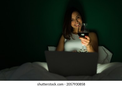 Cheers! Super Happy Woman In Bed Drinking Wine And Enjoying A Virtual Date During A Video Call 