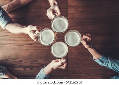 Cheers! Top View Of People Holding Mugs With Beer.