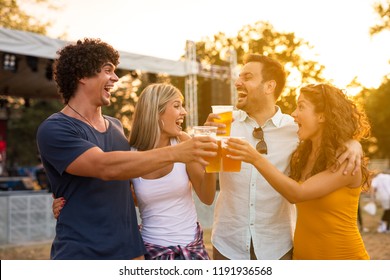 Cheers to us! Happy friends cheering with beer and looking at each other. Enjoying life at music festival.