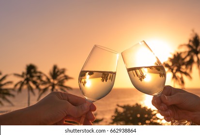 Cheers With Wine Glasses In A Beautiful Sunset Beach Setting. 