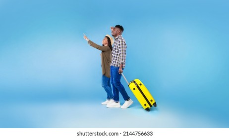 Cheery Millennial Black Couple Walking With Suitcase, Traveling Together, Having Summer Vacation On Blue Studio Background, Banner Design. Young African American Spouses Having Tour, Enjoying Voyage