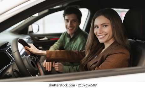 Cheery Young Couple Sitting Inside New Car, Checking It Before Purchase At Dealership Store, Banner Design. Cheerful Millennial Spouses Purchasing Or Renting Automobile At Showroom, Copy Space