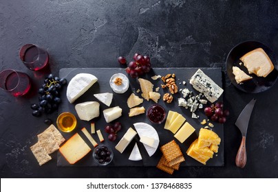 Cheese assortment on slate cutting board with wine. Grey background. Top view. Copy space. - Powered by Shutterstock