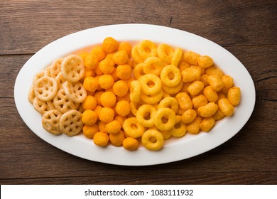 Cheese balls / rings, Corn Puff with crispy salty Wheel fryums. Served in a white plate or wooden bowl. Selective focus 
