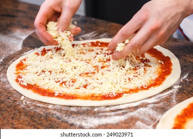 Cheese being spread on tomato sauce on pizza base. - Powered by Shutterstock