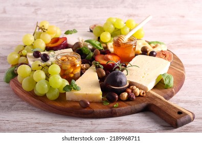 Cheese board: appetizers board with assorted cheese, fruits, honey and nuts -charcuterie board - Shutterstock ID 2189968711