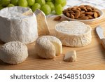 Cheese board with French Chaource cheese , Pico goat cheese and Crottin de chevre cheese close up with grapes and almonds on the background