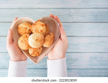 Cheese bread (brazilian Pao de Queijo mineiro) and coffee, heart-shaped plate, woman's hand, top view flat lay - Powered by Shutterstock