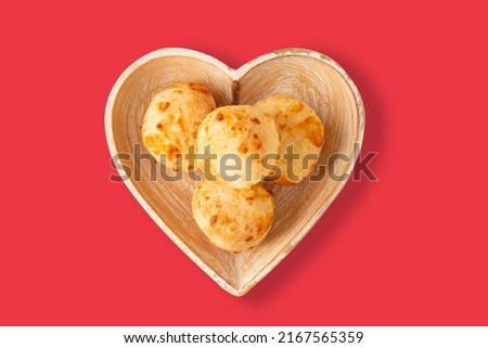 Cheese bread (Brazilian pao de queijo mineiro), top view, pink background, on a heart shaped plate.