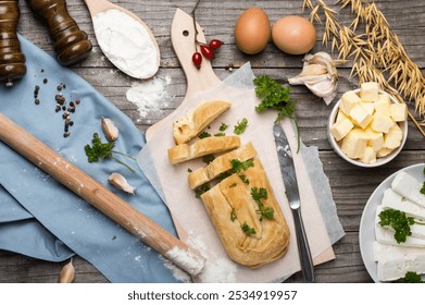 Cheese burek on Wooden Board with Rustic Cooking Ingredients. Puff Pastry and Fresh Ingredients Ready for Cooking, Rustic Style. Balkan national dish. - Powered by Shutterstock